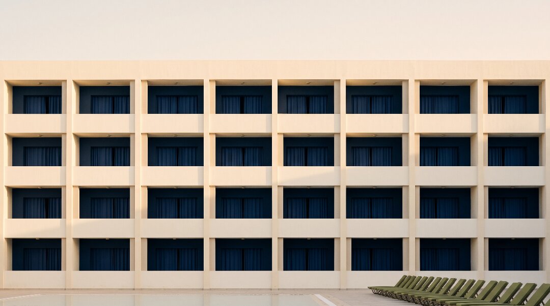 Repeating rows of identical hotel balconies above an empty pool deck at dawn in Hurghada