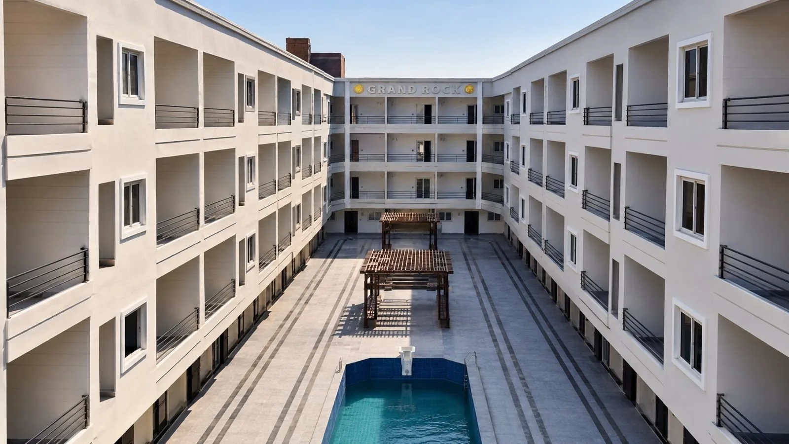 صورة حقيقية: Inner courtyard with pergolas and pool, Grand Rock sign on the end block, October 2026