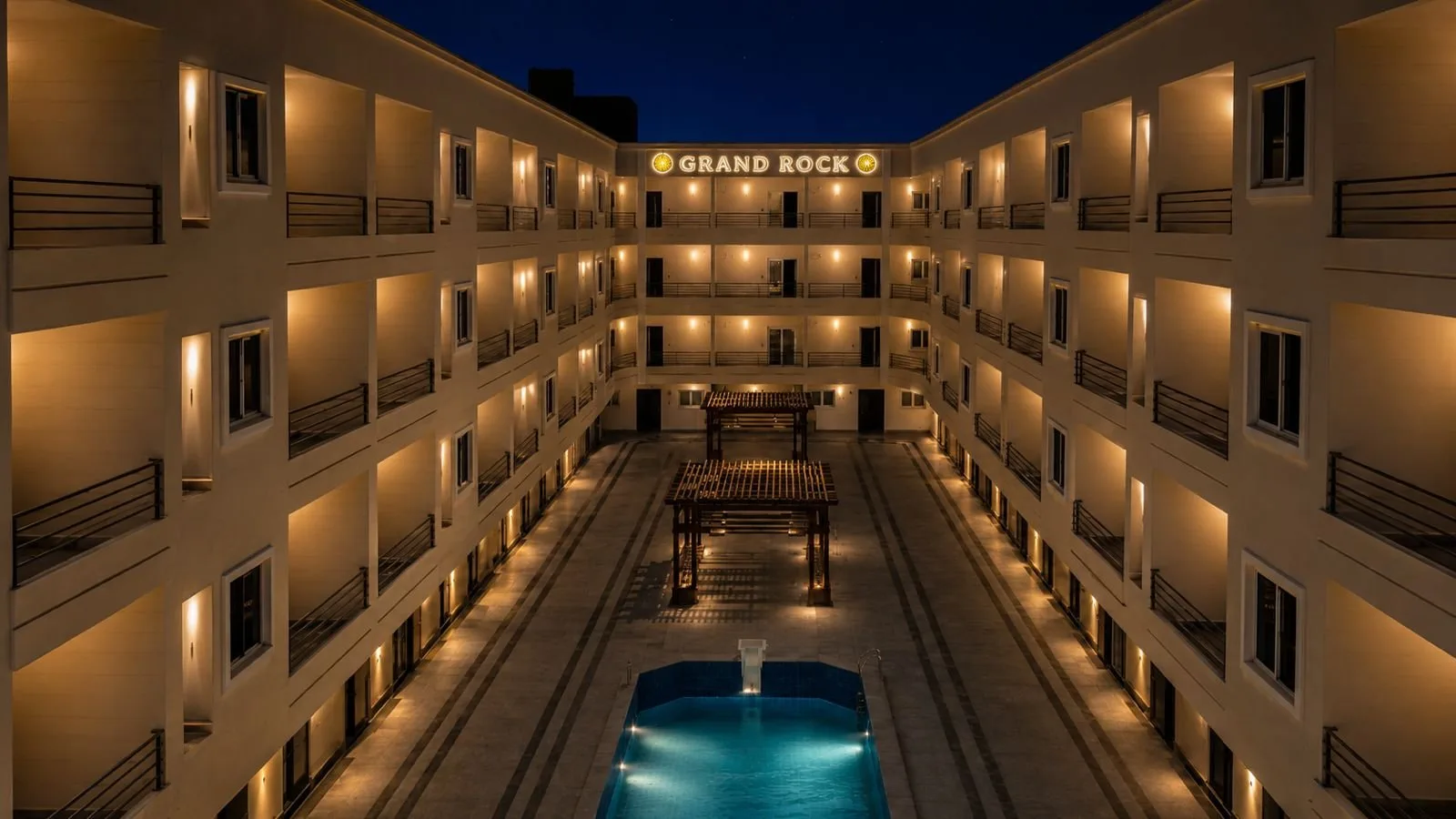 صورة حقيقية: Lit courtyard and pool between residential blocks, October 2026